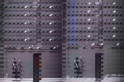 Outside wall with many security cameras pointing down at 2 people at a door